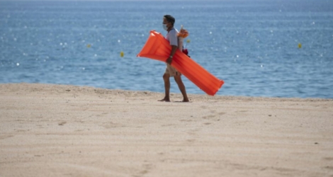 Un vacancier porte un masque de protection sur la plage de Lloret de Mar, le 22 juin 2020 en Espagne Photo Josep LAGO. AFP