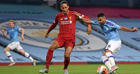 L'attaquant algérien de Manchester City Riyad Mahrez (d) tire et marque devant le défenseur néerlandais de Liverpool Virgil van Dijk, mais le but sera annulé par la VAR, le 2 juillet 2020 à Manchester.