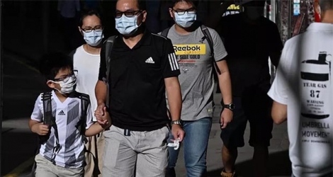 Des piétons portent un masque de protection dans une rue de Hong Kong, le 27 juillet 2020.