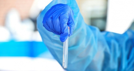 Un employé médical tient un tube à essai contenant un échantillon de test du coronavirus effectué sur la plage de Revere Beach, Massachusetts, le 11 août 2020.