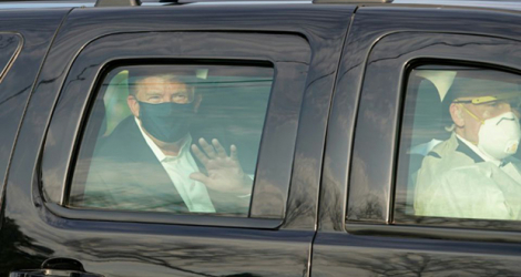 Le président américain Donald Trump salue ses symathisants depuis la limousine présidentielle lors d'une brève sortie de l'hôpital militaire de Walter Reed à Bethesda, près de Washington, le 4 octobre 2020.