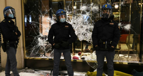 Des policiers surveillent une vitrine vandalisée par des manifestants le 26 octobre 2020 à Turin (Italie) Photo Marco BERTORELLO . AFP