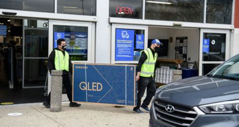 Des employés transportent un téléviseur à écran plat à la voiture d'un client, pendant le Black Friday, le 27 novembre 2020 à Wheaton, dans le Maryland.
