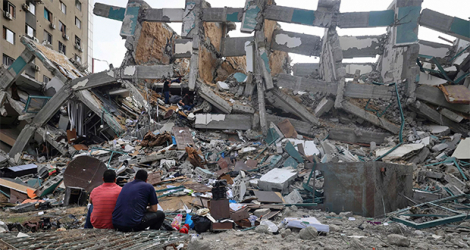 Des Palestiniens sont assis devant un bâtiment détruit par une frappe aérienne israélienne, dans la ville de Gaza, le 21 mai 2021, après qu'un cessez-le-feu ait été conclu entre Israël et le Hamas.