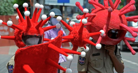 Des policiers portant des déguisements sur le thème du coronavirus, pour inciter les habitants à respecter les restrictions sanitaires, sont postés à un carrefour de Hyderabad (Inde), le 27 mai 2021. afp.com - NOAH SEELAM