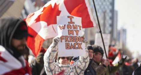 Des manifestants brandissent une pancarte contre les restrictions sanitaires et un drapeau canadien lors d'une manifestation à Toronto, Ontario, Canada, le 5 février 2022. afp.com - Geoff Robins