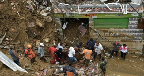 Des habitants évacuent le corps d'une victime après des glissements de terrain et des inondations à Petropolis, le 16 février 2022 au Brésil.