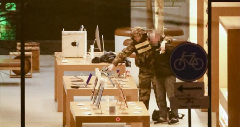 Un preneur d'otage (g) retient une personne par le cou dans un magasin Apple Store à Amsterdam, le 22 février 2022.