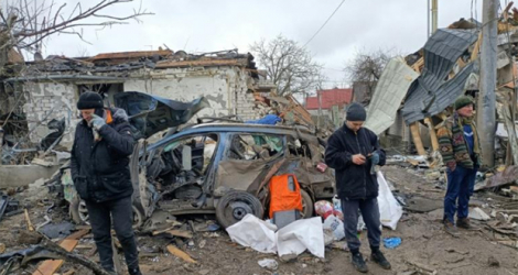 Trois hommes devant des ruines provoquées par un bombardement des forces russes à Jitomir, en Ukraine, le 2 mars 2022.