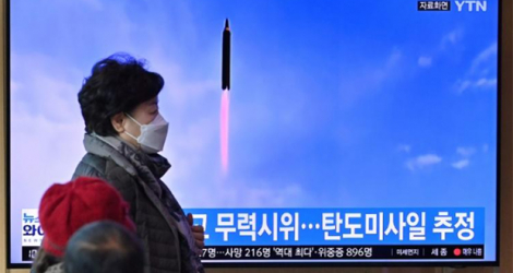 Des passants devant une télévision qui diifuse des images d'un essai d'armement réalisé par la Corée du Nord, à Séoul le 5 mars 2022.