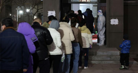 Des habitants d'un quartier résidentiel de Changchun, en Chine, font la queue pour se faire dépister le 11 mars 2022.