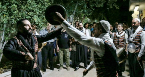 Des danseurs de la troupe Bab al-Hara agitant des épées et des boucliers en l'air lors d'une fête à Amman, le 24 juin 2022.