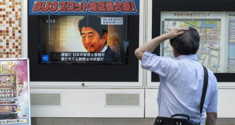 Un passant devant un écran diffusant la nouvelle de l'assassinat par balles de l'ex Premier ministre Shinzo Abe, à Tokyo le 8 juillet 2022.