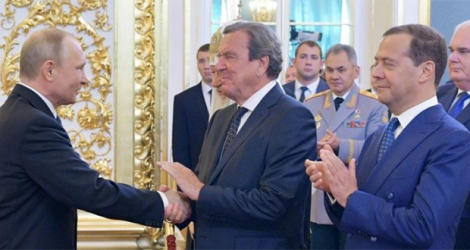 Le président russe Vladimir Poutine (gauche) serre la main de l'ex-chancelier allemand Gerhard Schröder le 7 mai 2018 au Kremlin à Moscou.