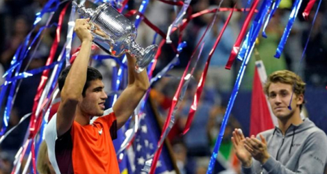 L'Espagnol Carlos Alcaraz (g) soulève le trophée de l'US Open après sa victoire en finale contre le Norvégien Casper Ruud, qui l'applaudit, à New York, le 11 septembre 2022.