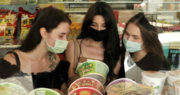 Trois étudiantes ukrainiennes, Anna Fursyk, Karyna Myshnova et Alina Kuprii comparent des paquets de nouilles instantanées, à Taichung, dans le centre de Taïwan, le 22 juin 2022.